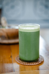 Glass of green celery juice on wooden table