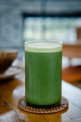 Glass of green celery juice on wooden table