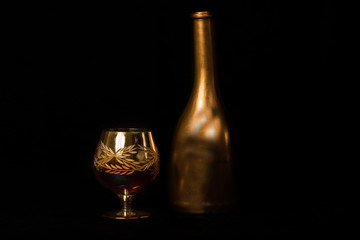 bottle and wine glass photographed on black background