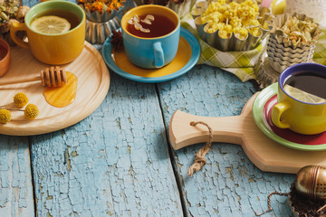 Cups with herb tea and pieces of lemon, dried herbs and different decorations