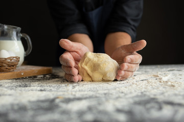 the ingredients for pizza are on the table, the chef's male hands knead the dough.