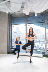 Fototapeta na wymiar Young adult mother and little daughter together practicing yoga