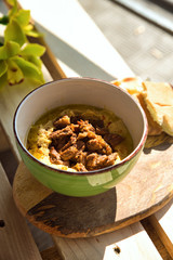 Chickpea hummus with stewed beef in a plate on wooden background