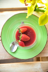 Panacota with strawberries in a cup on a wooden background with flowers
