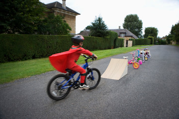 Young boy riding bicycle towards ramp