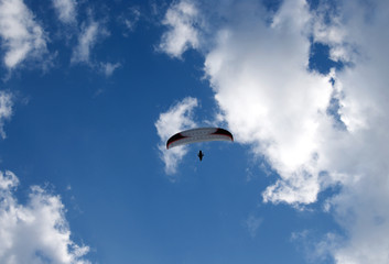 Photo of a parachutist over blue sky with clouds