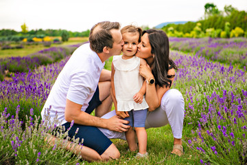 Happy family mother, father and daughter having fun in lavender field