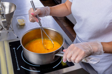 Pastry chef in the kitchen makes passion fruit confit. Cook mixes the fruits with a sugar in a saucepan. Master class in the kitchen. The process of cooking. Step by step. Tutorial. Close-up