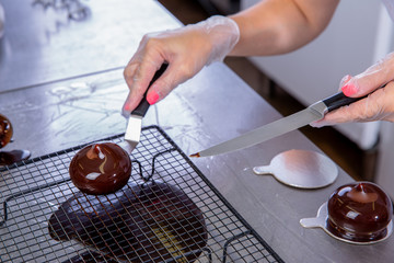 The pastry chef in the kitchen glazes pastries. Cook puts glazed cakes on decorative coasters. Master class in the kitchen. The process of cooking. Step by step. Tutorial. Close-up