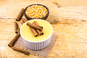 Dessert of curau. Brazilian sweet corn, corn mousse with cinnamon on a wooden background. Typical Brazilian dessert, sweet of June party. Dessert, canjica or Jimbelê.