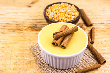Dessert of curau. Brazilian sweet corn, corn mousse with cinnamon on a wooden background. Typical Brazilian dessert, sweet of June party. Dessert, canjica or Jimbelê.