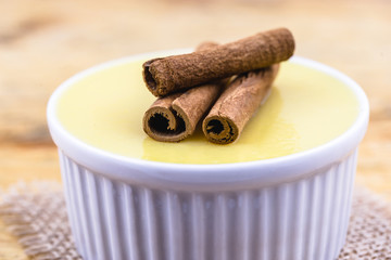 Dessert of curau. Brazilian sweet corn, corn mousse with cinnamon on a wooden background. Typical Brazilian dessert, sweet of June party. Dessert, canjica or Jimbelê.