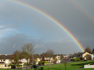 Colorful rainbow over small city houses, Green lawn.
