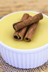 Dessert of curau. Brazilian sweet corn, corn mousse with cinnamon on a wooden background. Typical Brazilian dessert, sweet of June party. Dessert, canjica or Jimbelê.