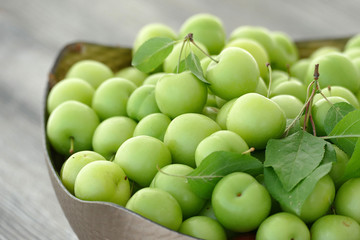 close-up of green sour plums, a container of plums, fresh green plums,