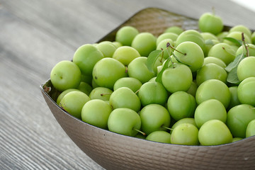 close-up of green sour plums, a container of plums, fresh green plums,