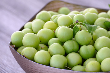 close-up of green sour plums, a container of plums, fresh green plums,