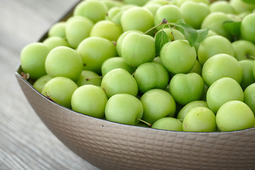 close-up of green sour plums, a container of plums, fresh green plums,