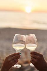 Couple clinking glasses of champagne at sunset
