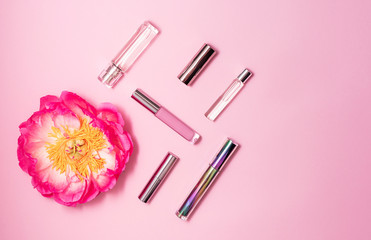 Flat lay composition with decorative makeup products, perfume and peony on pink background. Makeup and beaty concept. Copy space.