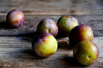 Plums in the garden in the morning, on old boards.