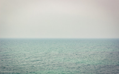 Obraz premium wavy Mediterranean sea in morning foggy cloudy weather time with unfocused horizon line and gray empty sky, simple natural background wallpaper pattern. copy space for text
