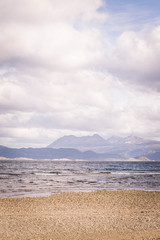 Fototapeta na wymiar Playa de un lago con montañas detrás, en Ushuaia, Argentina