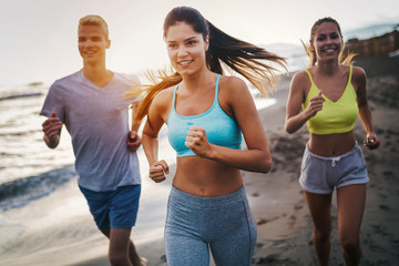 Group of athletes running on ocean front. Friends in sportswear training together outdoors.