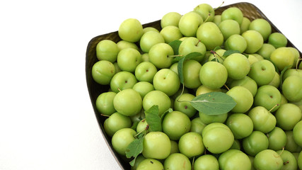 green plums, fresh plums, sour plums in a container, green and sour plums close-up,