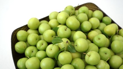 lots of green and sour fresh plums, on white background