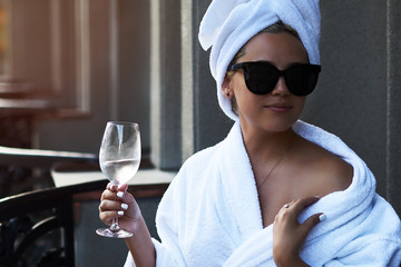 Beautiful blonde in white coat and sunglasses enjoy a glass of champagne