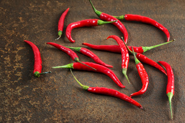 Pods of hot red pepper on a rusty metal surface. 