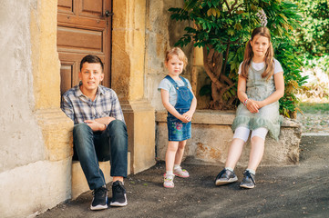 Obraz na płótnie Canvas Portrait of three funny kids posing outdoor, teenage boy with little sisters, happy family