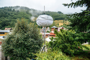 Mobile meteo station with houses of Ottenhofen im Schwarzwald, Germany in the background and green forest covered with fog