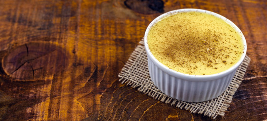 Brazilian sweet corn, corn mousse on a wooden background with copy space. Typical Brazilian dessert, sweet of mingua, called in Brazil of curau. Typical sweet of June party.