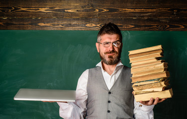 Modern education. Smiling male student holds traditional textbook and reading e-books. Book vs...