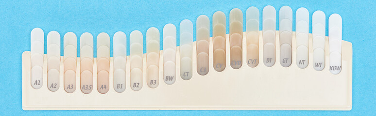 Obraz premium panoramic shot of teeth samples with different shades isolated on blue