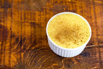 Dessert of curau. Brazilian sweet corn, corn mousse with cinnamon on a wooden background. Typical Brazilian dessert, sweet of June party. Dessert, canjica or Jimbelê.