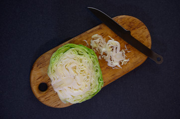 Chopping cabbage on a cutting board with a black knife, top view