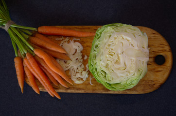 Chopped cabbage and small carrots on a cutting board, top view