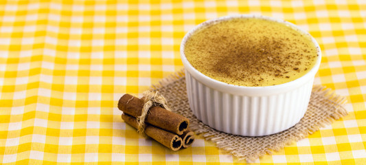 Brazilian sweet corn cream, Dessert, canjica or Jimbelê, dessert cured corn corn mousse with cinnamon on a wood background. Copy space