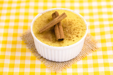 Dessert of curau. Brazilian sweet corn, corn mousse with cinnamon on a wooden background. Typical Brazilian dessert, sweet of June party. Dessert, canjica or Jimbelê.