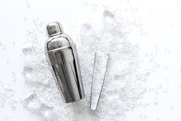 Frozen water in ice cubes and shaker on marble bar table top view