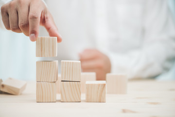 Hand arranging three wood cube stacking. Business concept growth success,hand stack woods block step on table. business development concept.copy space.