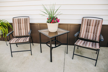 outdoor patio with two chairs and a small table and a plant