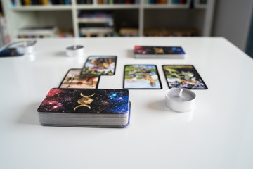 Close up on tarot card reading opening cards at home on the white table with candles beside fortune telling future predicting