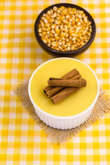 Dessert of curau. Brazilian sweet corn, corn mousse with cinnamon on a wooden background. Typical Brazilian dessert, sweet of June party. Dessert, canjica or Jimbelê.