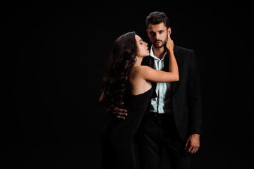 passionate girl in dress touching handsome bearded man isolated on black