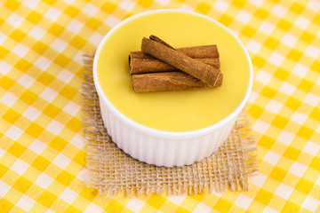 Dessert of curau. Brazilian sweet corn, corn mousse with cinnamon on a wooden background. Typical Brazilian dessert, sweet of June party. Dessert, canjica or Jimbelê.