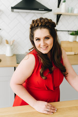 A portrait of beautiful woman in red dress sitting at the kitchen table 